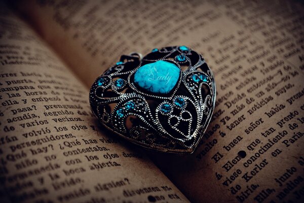 Pietra turchese a forma di cuore su uno sfondo di pagine di libri