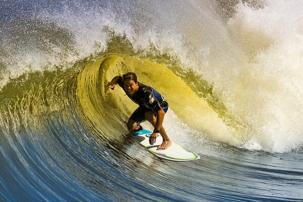 Ein fröhlicher Surfer auf einem Brett, der eine tolle Welle gefangen hat