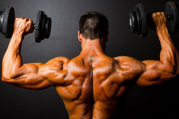 A muscular hard athlete does exercises on his hands