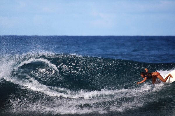 Jeune fille debout sur une planche de surf sur une vague