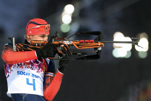 Поясное фото биатлониста Антона Шипулина, целящегося из винтовки в ходе соревнований на зимних олимпийских играх Сочи-2014