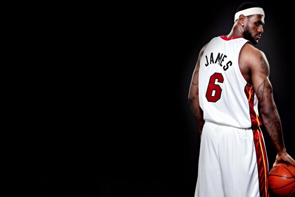 Photo of a basketball player James LeBron turning around in a white uniform on a black background