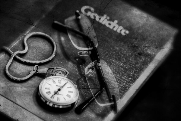 El reloj y las gafas se encuentran en el libro, blanco y negro