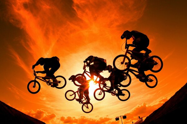 The jump of a group of cyclists on the background of sunset