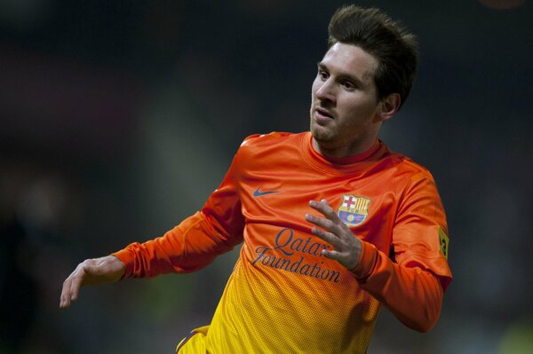 Foto in vita del calciatore in corsa Dell FC Barcelona Lionel Messi in una maglia a maniche lunghe gialla e arancione