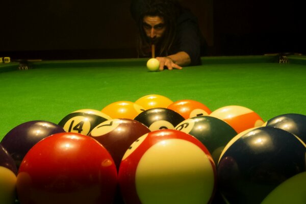 A man is playing billiards with colored balls