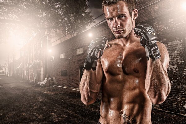 A fighter in gloves on the background of a building