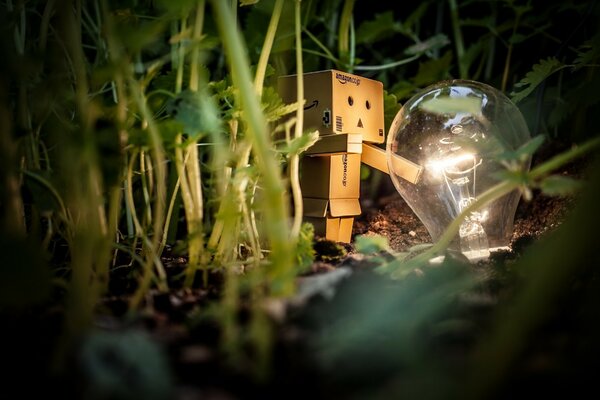 A light bulb in the grass next to a homemade robot