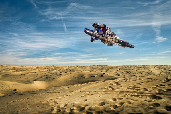 Motorcycle in the air against the background of sand and sky