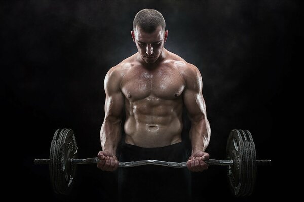 The guy performs a physical exercise with a barbell