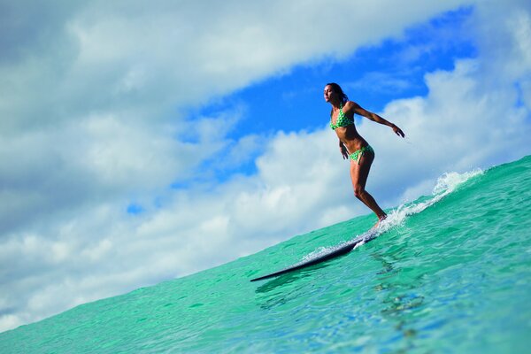 Surfeur fille sur un tableau noir sur fond de mer et de ciel