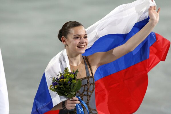 Sotnikova avvolta dalla nostra bandiera su una pista di pattinaggio con un bouquet