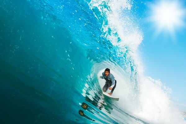 Surfing in the sea on a board, passing a surfer under the crest of a wave