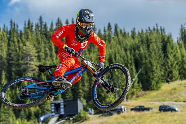 Carrera de bicicletas salto participante en traje rojo en bicicleta azul