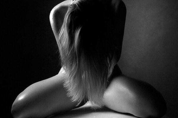 Naked girl covers her private parts with long hair in a black and white photo