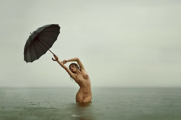 Naked girl in the water under an umbrella