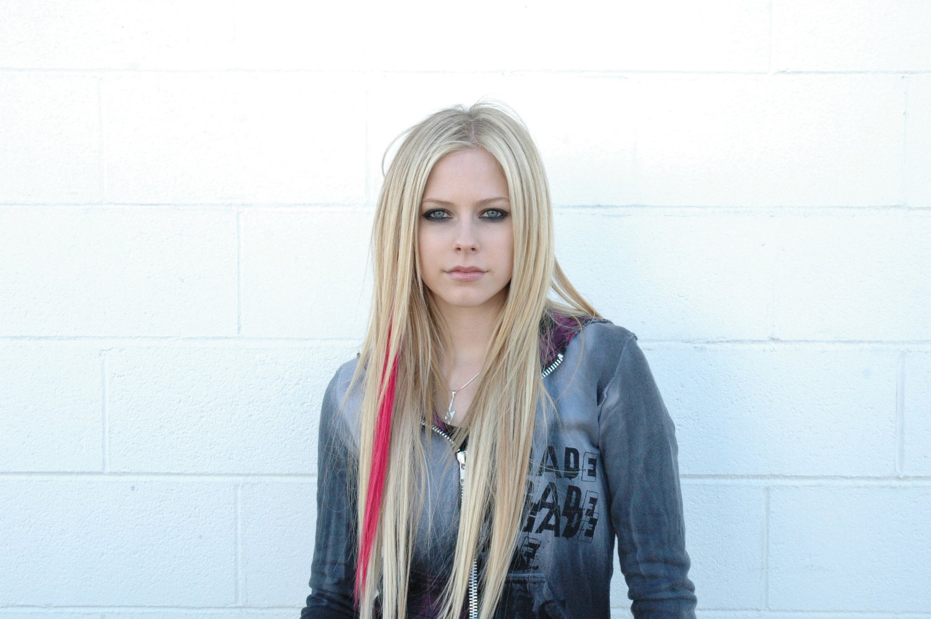 girl avril lavigne famous rock singer is on the white wall looks at the camera strip of hair