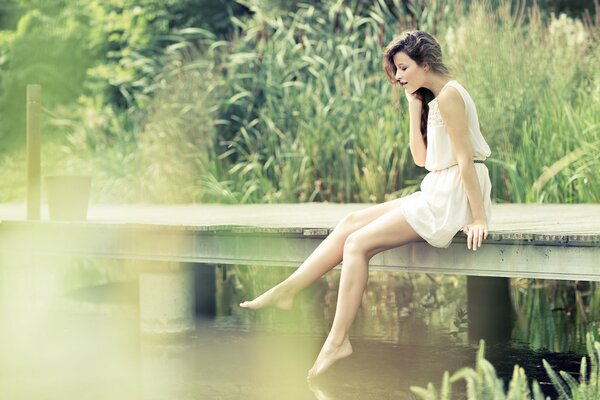 Chica sentada en la naturaleza junto al río