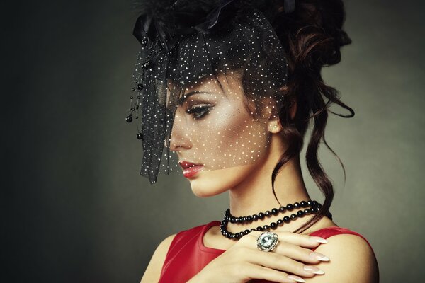 A model in a red dress and behind a veil