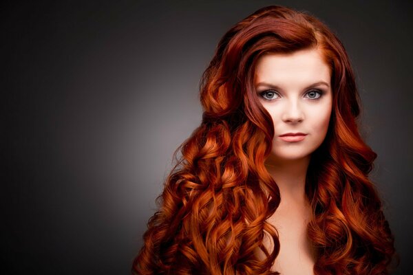 A girl with thick and red hair on a dark background