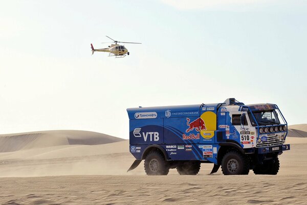 Camión de carreras en el desierto con helicóptero