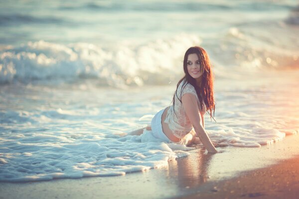 Girl in a wet tank top on the beach on the water