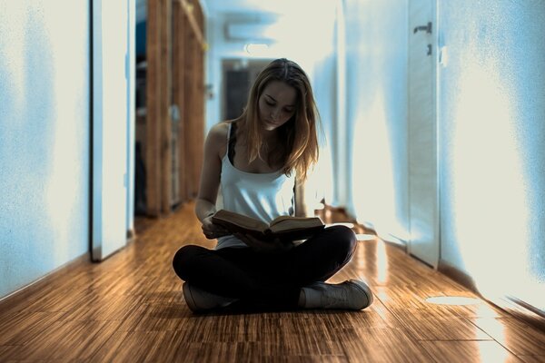 Una chica se sienta en el pasillo en el Suelo y Lee un libro