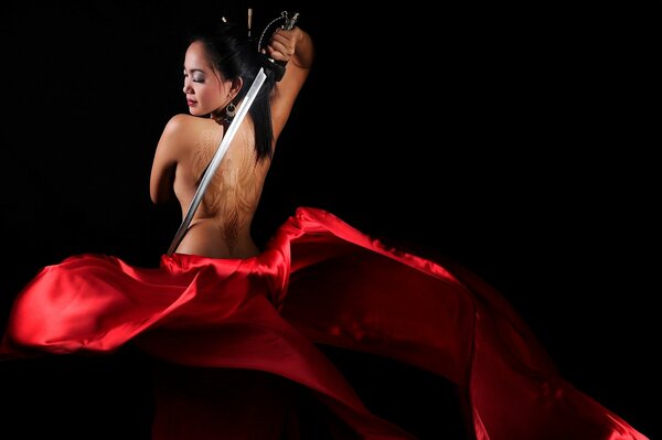 A girl in a red dress dancing with a sword