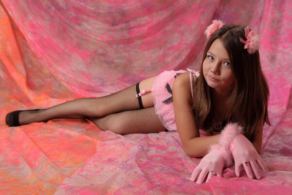 Pink view, a teenager lies with her legs straightened in heels in underwear and stockings