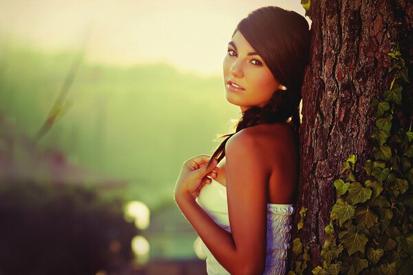 Foto di una ragazza vicino a un albero alla luce del sole