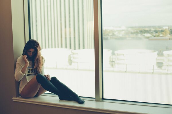 Beautiful brunette in leggings on the window sill