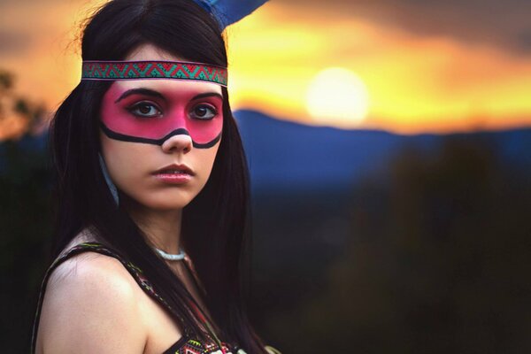 Chica con la cara pintada en el fondo de la puesta de sol