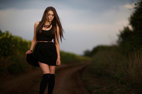 Tina en un vestido negro y en la rodilla en la carretera