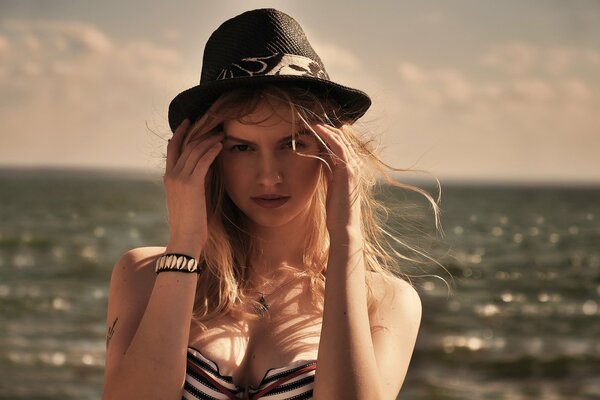 Ragazza con cappello su sfondo di nuvole e mare