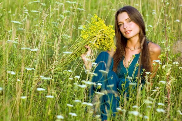 Mädchen auf einem Sommerfeld umgeben von Wildblumen