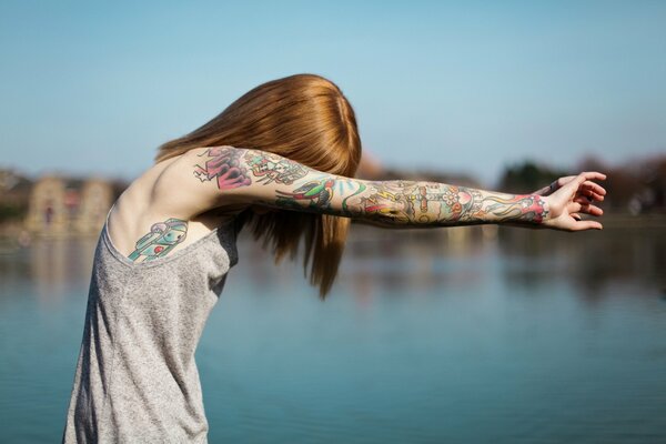 A girl with a tattoo on the whole arm on a blurry background