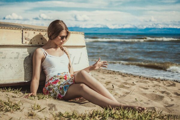 A girl by the sea is resting by the boat