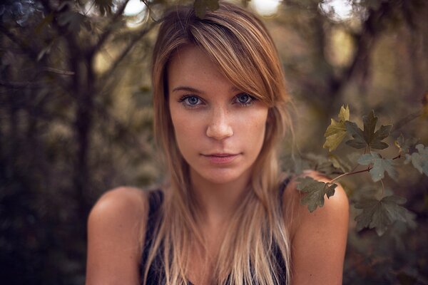 A girl with blonde hair against a background of trees