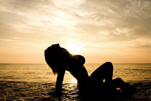 Chica en el mar en el fondo de la puesta de sol