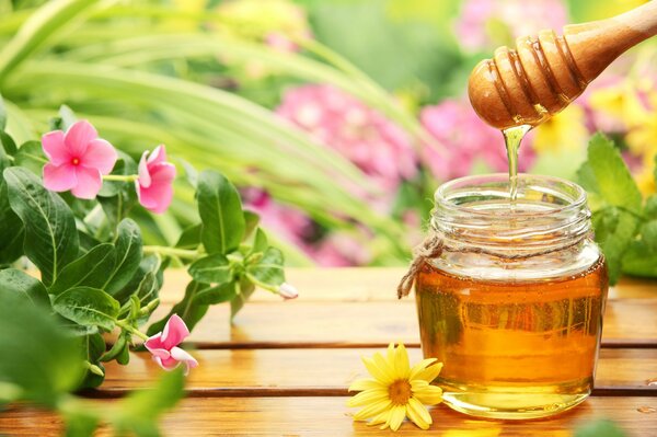 Pot de miel sur la table parmi les fleurs