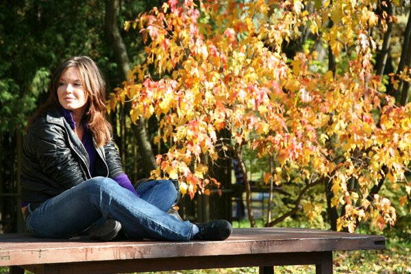 Ragazza seduta su una panchina in autunno