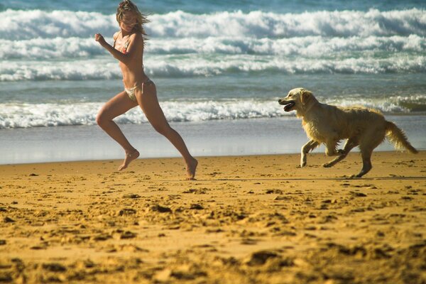 Fille et chien courant sur la plage