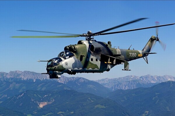 Hélicoptère de transport et de combat sur fond de montagnes et de ciel bleu