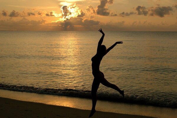 Fille sur la plage sur fond de coucher de soleil