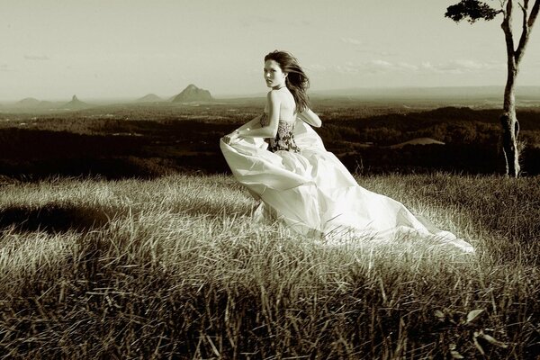 A girl in a long beautiful dress runs through the grass