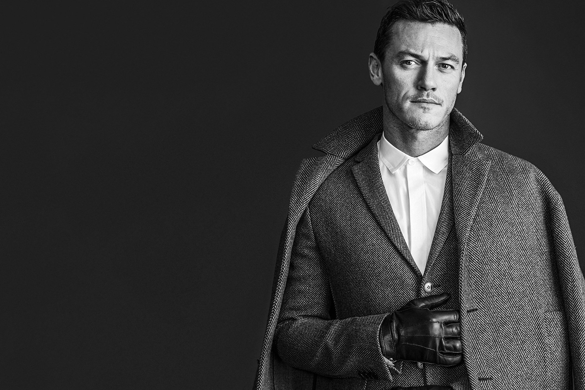 luke evans acteur manteau veste gant photo noir et blanc fond magazine wwd rodolfo martinez