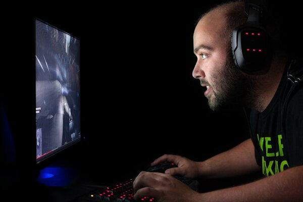 A male gamer is sitting at the monitor