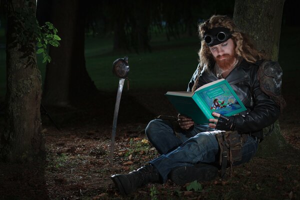 Длинноволосый мужик с бородой читает книгу сказок в лесу