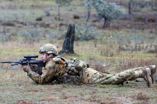 Ein Soldat mit einer Waffe im Hinterhalt liegt auf dem Bauch