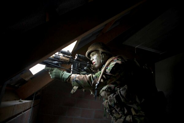 A soldier with a gun in his hands in the attic